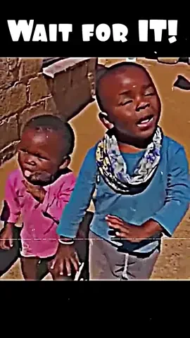 Two children stand by a wall beneath Wait for it.