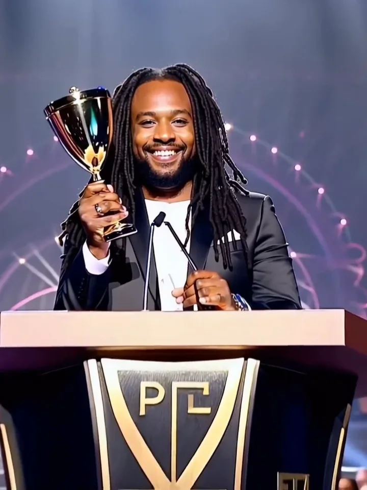 A smiling man raises a trophy at a podium.